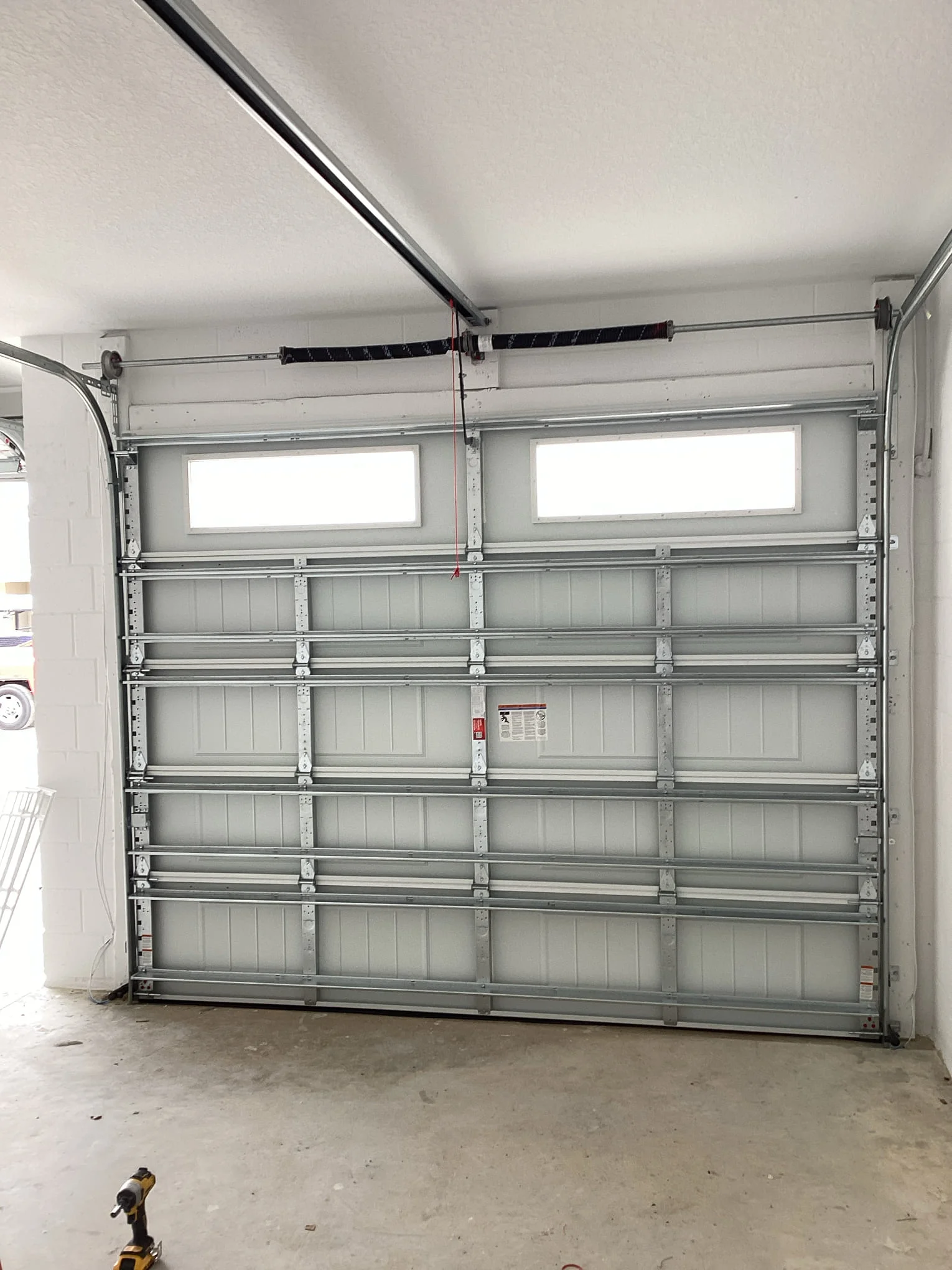 An interior view shows a reinforced steel garage door panel assembly with dual torsion springs, highlighting common garage door materials.