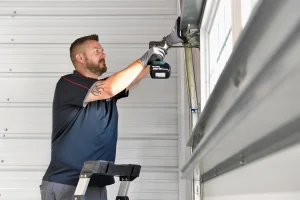 A technician on a stepladder uses a power drill to secure the upper hardware, demonstrating essential garage door installation tips.