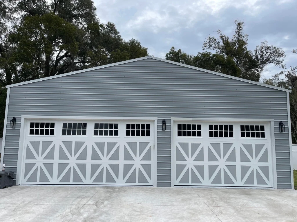 Two durable carriage-house style doors with window grids are installed on a reinforced metal building, demonstrating how to install a garage door that survives storm season.