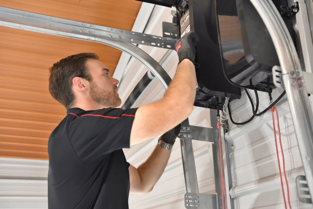 A technician works on a heavy-duty side-mount opener assembly attached to reinforced framing, providing specialized storm-focused garage door service.